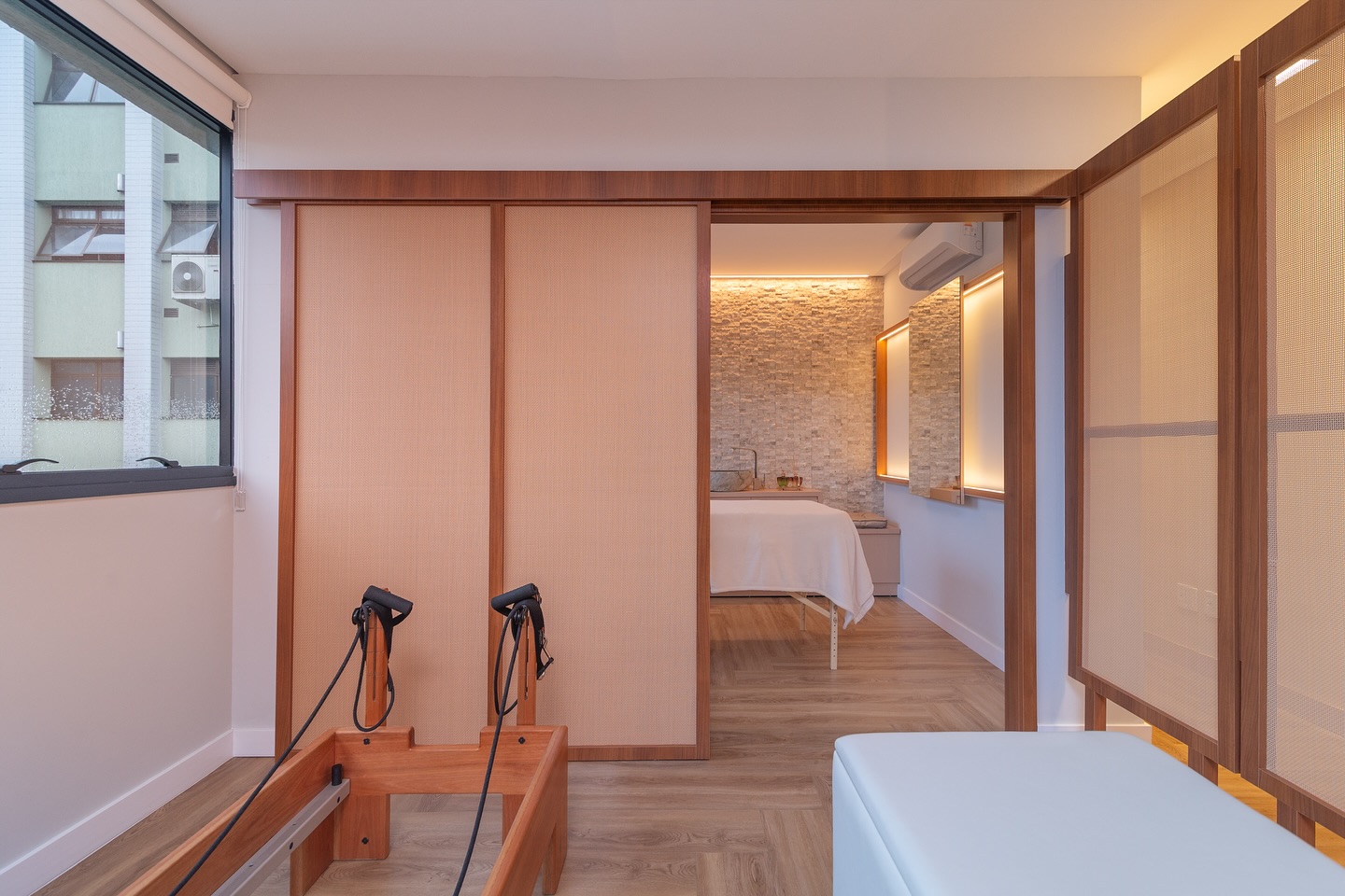 Painéis de correr em rattan abrindo para a sala de massagem